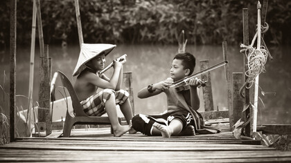 Dois irmãos orientais brincam com instrumentos de música