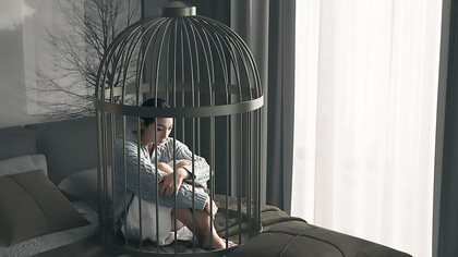 A woman practicing self-restraint lies in a bed cage, demonstrating control in a confined space