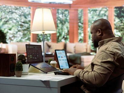 In a sleek architectural office, a man works on his computer, refining a digital twin of a building complex displayed through advanced 3D rendering software
