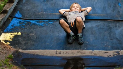 A child having what appears to be a pleasant dream as he lays in the middle of a wet road