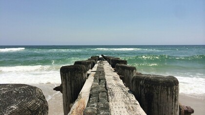 A weathered pier stretches into the Atlantic along North Carolina’s untamed coast, where history and natural beauty meet