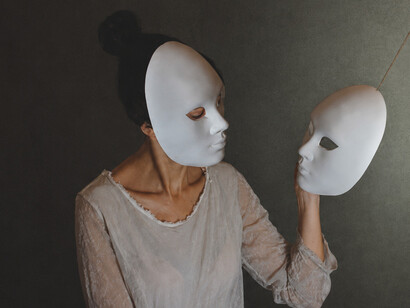 A woman removes a mask from her face only to reveal another beneath it, symbolizing the layers of identity people hide behind and the struggle to reveal their true selves