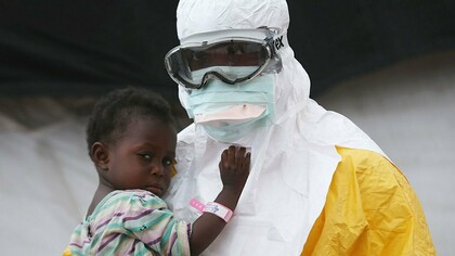 A doctor takes a child in his arms in Liberia