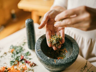 "A person preparing Ayurvedic medicine by pounding dried flowers with a mortar and pestle—symbolizing detox, healing, and the wisdom of ancient Indian medicine