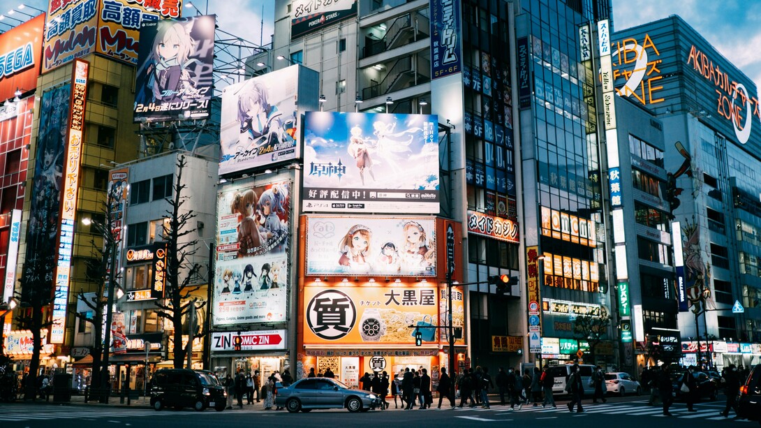 A bustling Tokyo district surrounded by towering anime billboards and media advertisements, symbolising the cultural prominence anime and manga have achieved in Japan and beyond