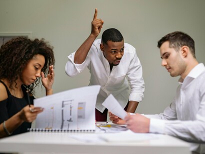 A leader asserting control during a tense meeting, reflecting the fear-driven silence that often develops within corporate teams