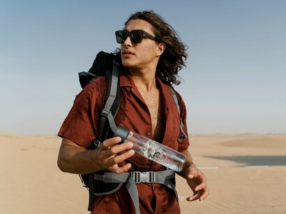 A backpacker holding a reusable water bottle during a journey, reflecting sustainable travel through simple, eco-conscious habits