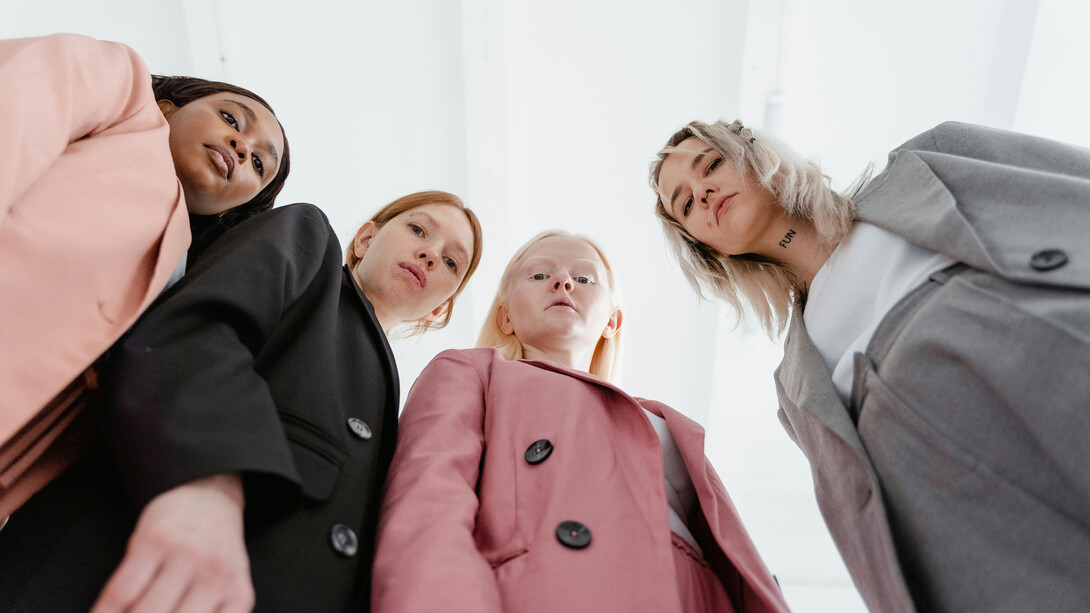 A group of women viewed from a low angle, looking confidently at the camera, symbolizing leadership and solidarity