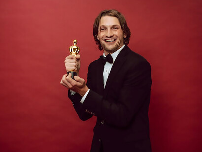 A man clad in a sharp suit proudly cradles an award, radiating happiness and strength, while exuding enthusiasm and ambition, embodying the epitome of success and accomplishment