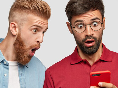 Two men looking angrily at their smartphone screens, reflecting the negative impacts of social media interaction