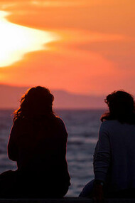 Dos amigas junto al mar contemplando la puesta de sol