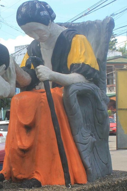 Old woman statue lowering her hand to receive mano gesture
