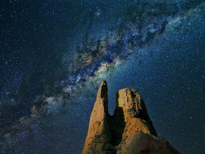 Rock formations illuminated by the night sky, within the embrace of the Solar System