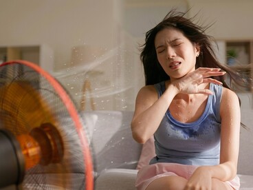 A woman tries to cope with the discomfort of extreme summer heat at home