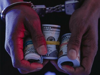 Bound wrists and bundled cash symbolize how justice is shackled while emoluments flow freely in a nation consumed by institutional rot