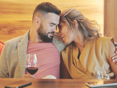 In the enchanting setting of their first date, a man and a woman meet at a charming venue, savoring the beginning of their connection over a shared glass of wine
