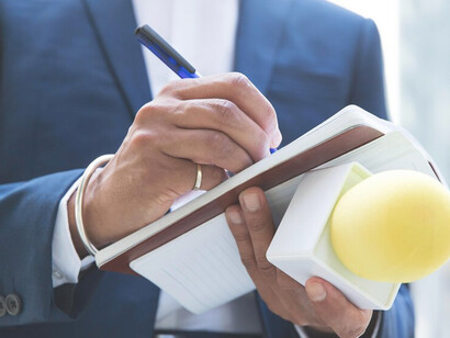 Reporter conducting an interview, taking notes and holding a microphone