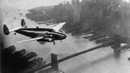 A twin-propeller Lockheed 14 Super Electra, flies over down town Manhattan and the Brooklyn Bridge, New York City. Inside, American millionaire Howard Hughes (1905 - 1976) and his crew fly round the world in four days. (Photo by Keystone/Getty Images)