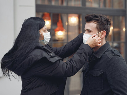 Ragazza aiuta amico ad indossare la mascherina per strada 