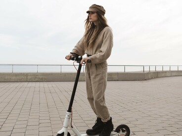 A young woman riding an electric scooter along a peaceful, walkable city street