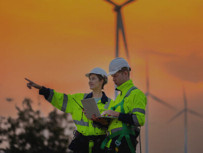 Engineers inspecting wind turbine construction at sunset, promoting clean energy and sustainability