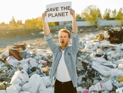 A man protesting in a landfill. The effects of the social environment an individual emerges from can wear out their effect in the face of willpower and a stronger influence