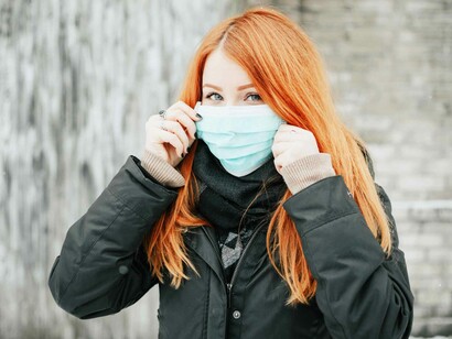 A young woman applying her mask as she prepares to greet society in this coronavirus pandemic world