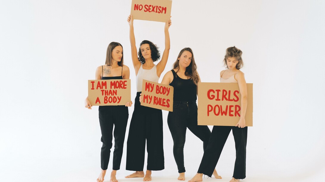 Mulheres de calças pretas segurando cartazes sobre o empoderamento feminino