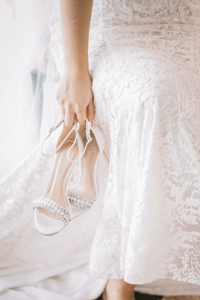 A pair of wedding shoes and a person wearing a white wedding dress