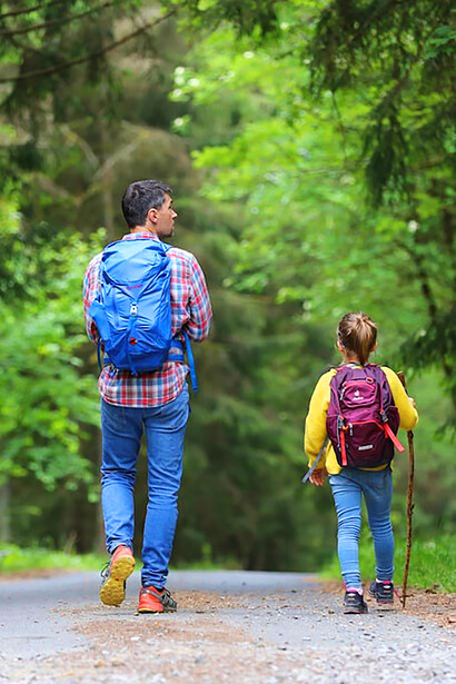 On this serene daytime stroll, a father proudly wearing a blue jacket and blue denim jeans is accompanied by his beloved daughter