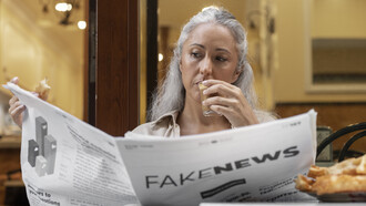 Una persona che legge un giornale intitolato “Fake News”