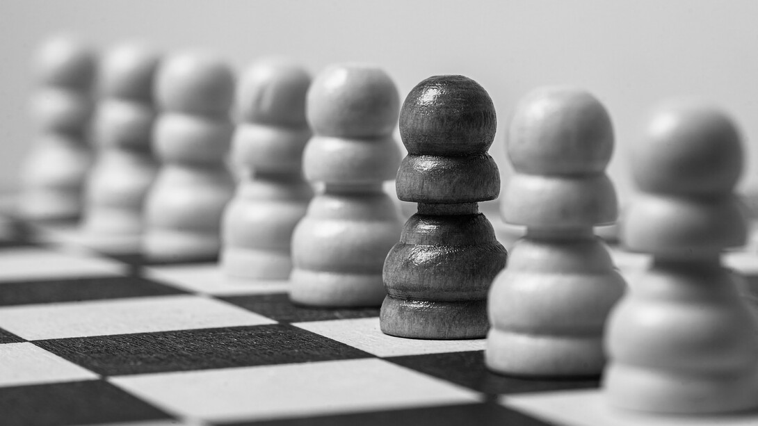 A solitary black pawn surrounded by a sea of white pawns on the chessboard