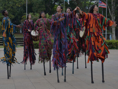 The group of stilt walkers tower above the onlookers, their vibrant, multi-coloured outfits adding a kaleidoscope of colour to the festival