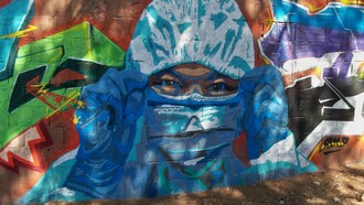 Mural de José Luis BorgArt, 2020, representando a un sanitario protegido con equipamiento contra la COVID-19, sobre el muro sur que delimita la finca de San José, Málaga, España