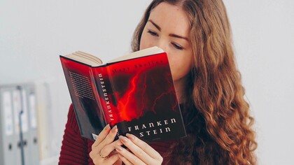 A woman enjoying her reading of a copy of Mary Shelly's novel Frankenstein