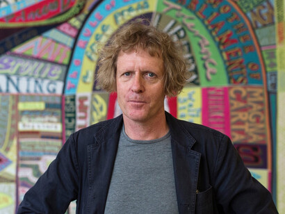 Artist Grayson Perry stands in front of a piece of his entitled 'Comfort blanket' at the National Portrait gallery. Courtesy of Mudac