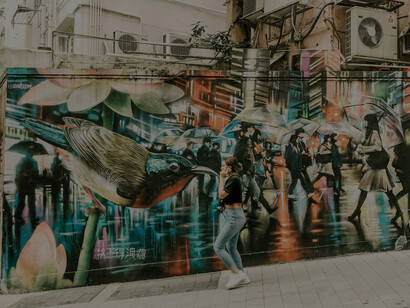 Woman walking past a graffiti-covered wall in Hong Kong