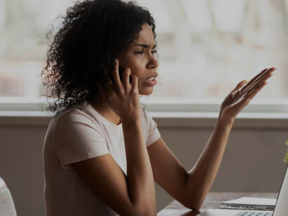 Anxious young businesswoman working alone, talking on the phone nervously