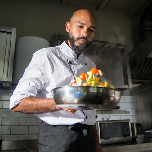 Chefe de cozinha olha concentrado os legumes cozidos na manteiga