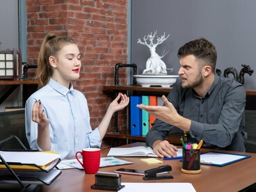 Two frustrated employees disagreeing openly, reflecting the consequences of misunderstanding and emotional reactions