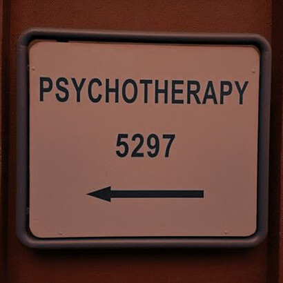 A dimly lit hallway with a sign saying "Psychotherapy 5297"