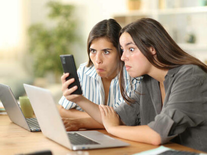 Shocked, two girls watch as hilarious memes flash across their screens