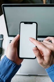 Jovem utiliza celular, relógio digital e laptop