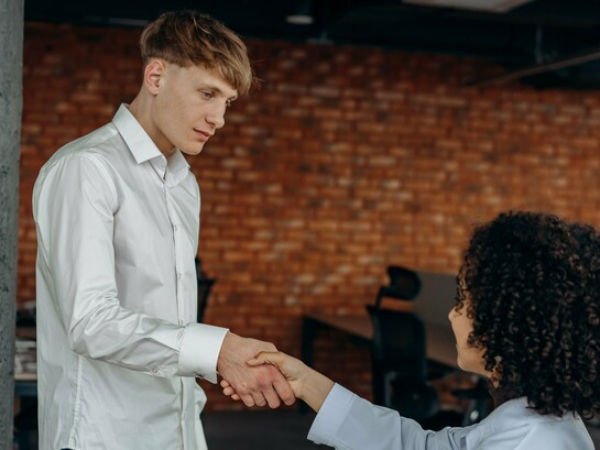 O aperto de mãos estabelece o contato entre duas pessoas, enquanto o semblante contido do homem revela outra dimensão da cena. Nem ausência completa de emoção, nem demonstração intensa de afeto: apenas a neutralidade de quem parece cumprir um gesto social. Quando até a interação humana pode se tornar automática, onde termina a cordialidade e começa a mornidão emocional? Há contato, mas pouca expressão; presença, mas uma distância difícil de nomear