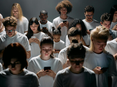 A large crowd, face down, staring at their phones