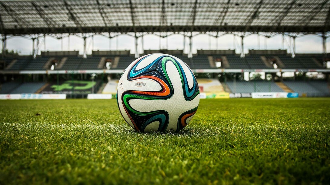 Balón de fútbol de varios colores ubicado en el campo de juego
