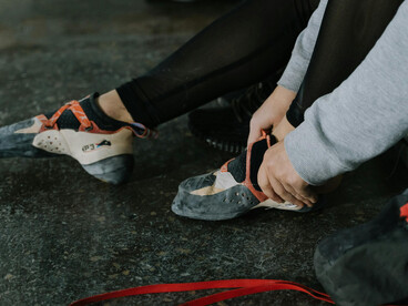 A cropped shot of a climber putting on her sneakers as she prepares for bouldering