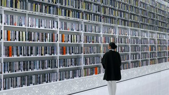 Mulher explora livros em estante de biblioteca