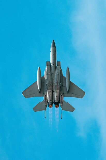 A fighter aircraft soaring overhead with its engines burning, reflecting the military blocs that divided the world into opposing camps