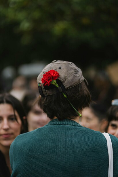 Pessoa jovem vista de costas usa um boné adornado com uma rosa. A imagem remete às novas gerações, frequentemente confrontadas com dificuldades de acesso à habitação, emprego estável e oportunidades